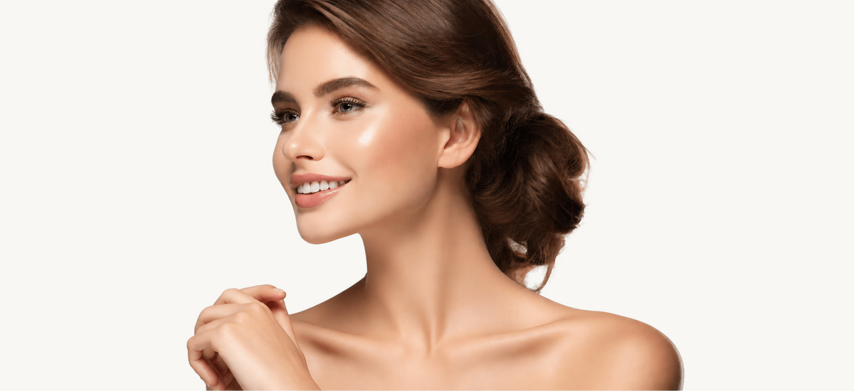 A close-up portrait of a smiling woman with warm, radiant skin and styled brown hair against a clean white background.